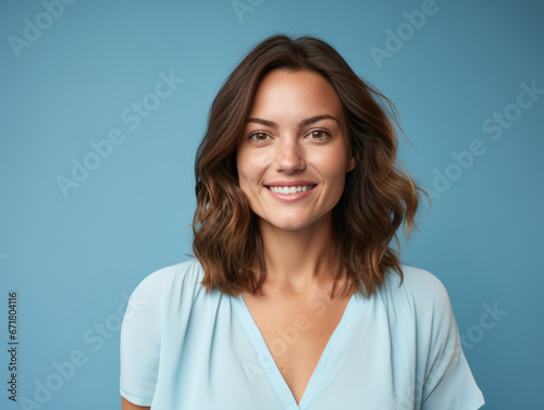 Closeup photo portrait of a young european woman smiling look at camera. Isolated on blue background.