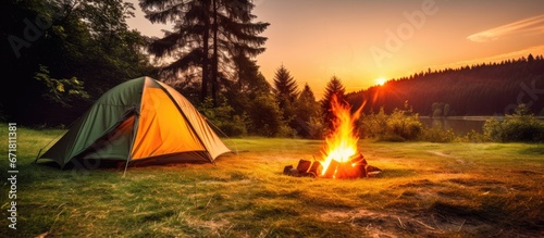 Yellow tent and warm bonfire in a beautiful green forest during summertime Sunrise camping routine Outdoor wanderlust