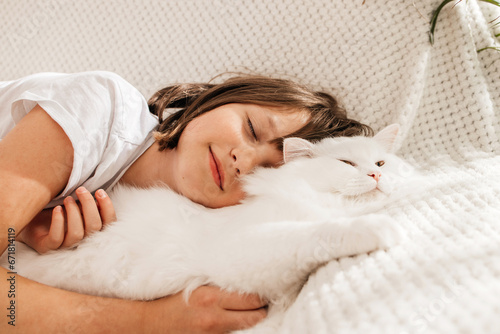 Close-up of a teenage girl lying on the sofa and hugging her favorite white fluffy cat. Children and animals. photo