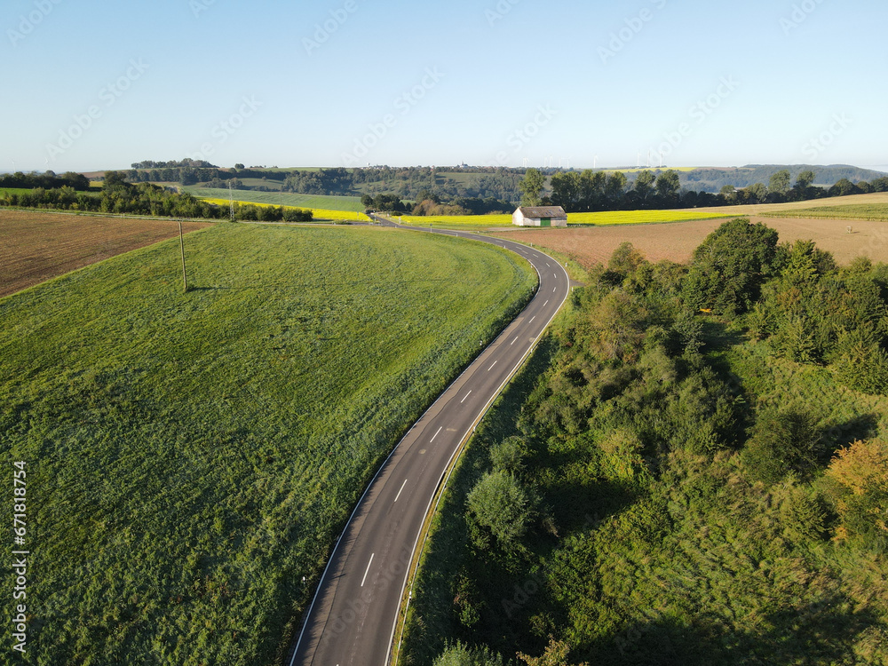 Naklejka premium Aerial view of a curved road in the landscape on a sunny morning in summer