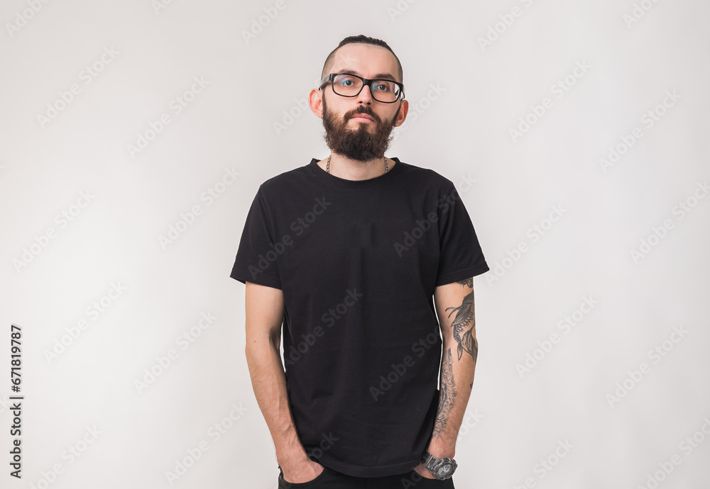 Portrait of attractive handsome man millennial with beard who looks into camera on isolated simple background and wears black t-shirt from premium organic materials Portrait of attractive handsome man millennial with beard who looks into camera on isolated simple background and wears black t-shirt from premium organic materials