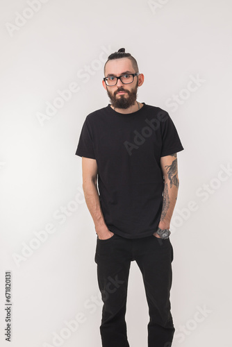 Portrait of attractive handsome man millennial with beard who looks into camera on isolated simple background and wears black t-shirt from premium organic materials