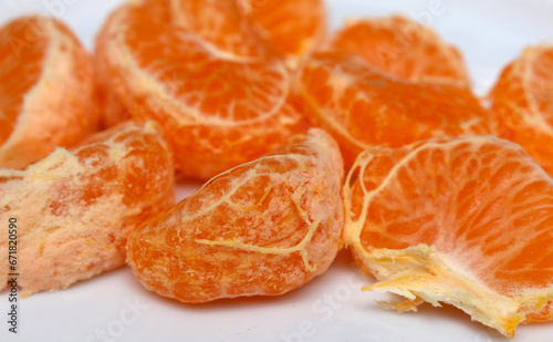 peeled tangerine on a white background. tangerine segments to be consumed. tangerine details. details of natural foods of plant origin. tangerine with selective focus.
