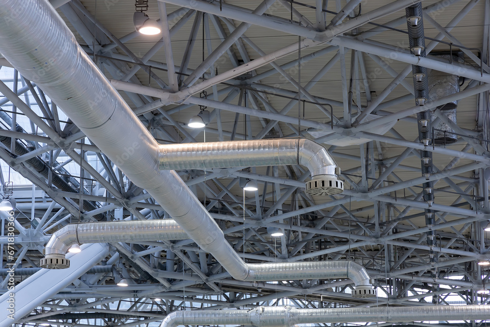 Ventilation in the exhibition pavilion or production plant or hangar or warehouse. Ventilation pipes duct tubes hanging from the ceiling. View from below. Fragment of the air ventilation system
