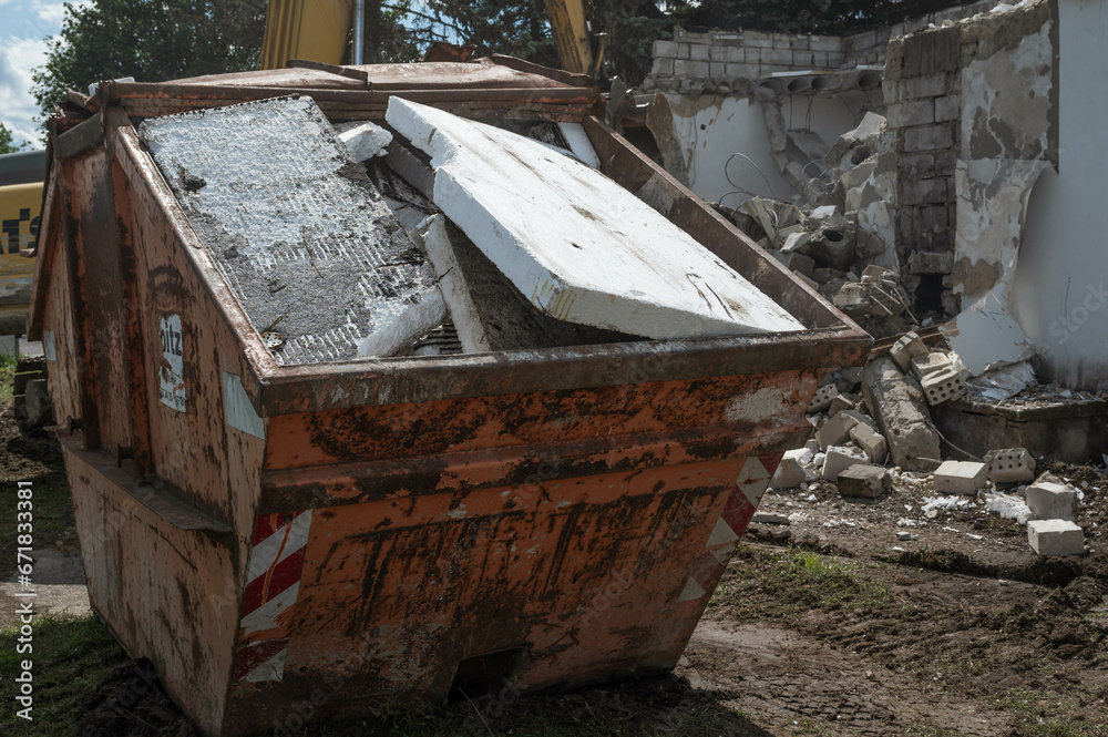 Styrofoam placed in a construction waste container, demolition of a building in the background Styrofoam placed in a construction waste container, demolition of a building in the background