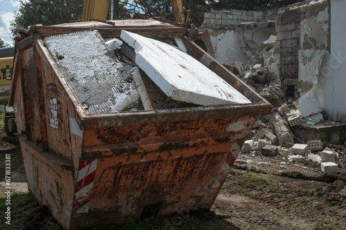 Styrofoam placed in a construction waste container, demolition of a building in the background
