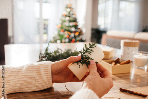 Close-up of a young woman's hands decorating candles for Christmas or New Year. Decorating items for the holiday and making gifts.