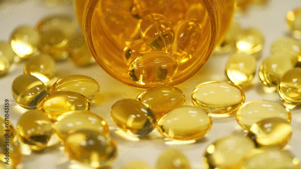 Yellow gel capsules with Omega-3 and an open jar lies on the table Yellow gel capsules with Omega-3 and an open jar lies on the table