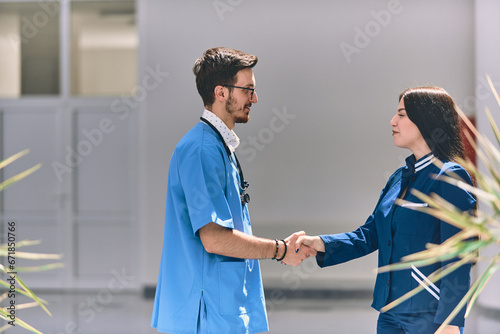A doctor and a nurse share a friendly handshake in the hallway of a large, modern hospital, symbolizing collaboration, trust, and dedication in healthcare