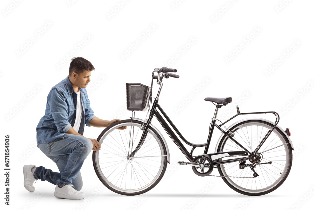 Young man kneeling and checking bicycle wheel - obrazy, fototapety, plakaty 