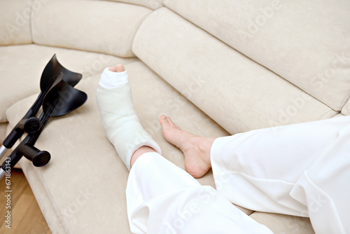 Fototapeta Broken leg in a plaster cast, near a crutches