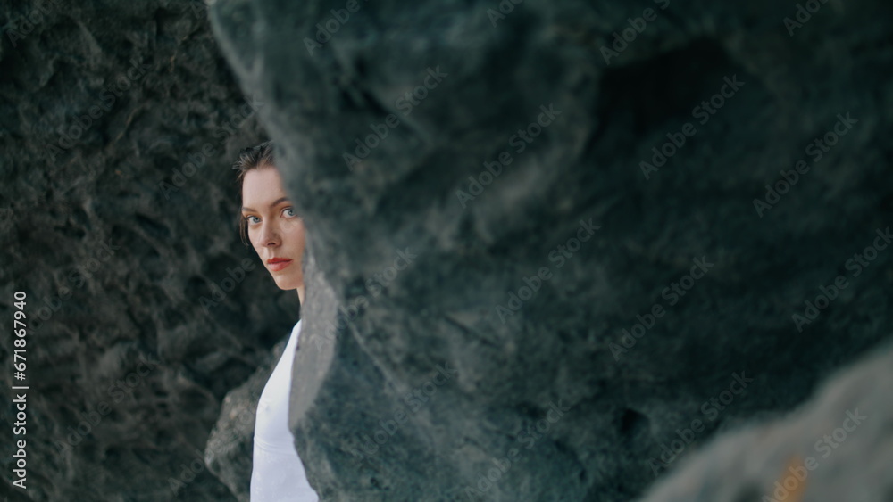 Closeup woman posing cliff wearing white swimsuit. Model posing leaning on rock.