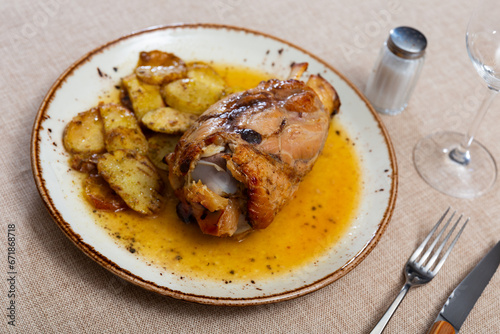 Appetizing pork knuckle baked in oven with boiled potatoes in white plate