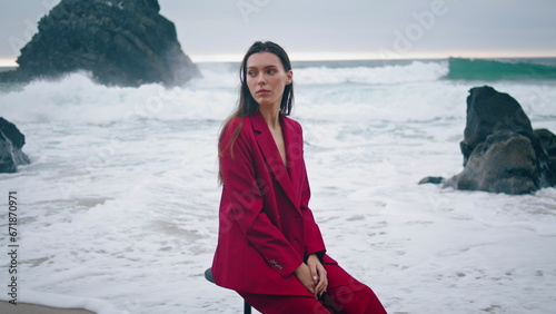Tranquil woman sitting waves stormy ocean closeup. Girl in red suit posing beach