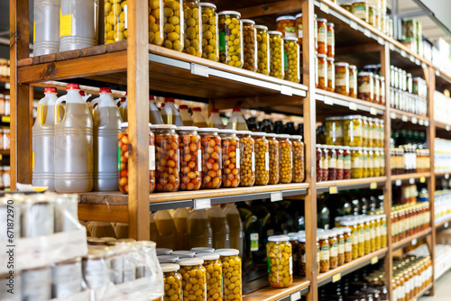 Cans tins of canned green olives are on supermarket shelf. Cans of preserves, olives of different varieties are displayed in window,shelf, store