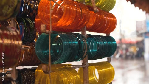 A set of colorful, handmade, traditional Indian glass bangles hanging in the shop. Rainy Day. Shallow depth of field.  