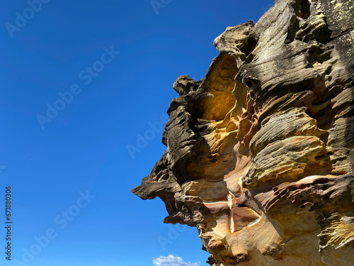 Rock formation under a blue sky. Ochre and brown rock undulating in the sun. Mineral kingdom on the coast. Wind-sculpted ore. Coastal landscape. Canyon geology.