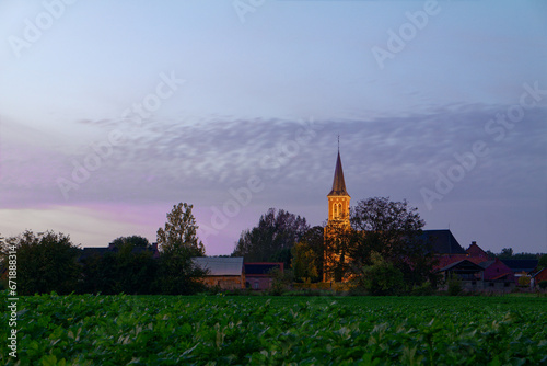 Oświetlony kościół w Belgii, krajobraz na wsi.