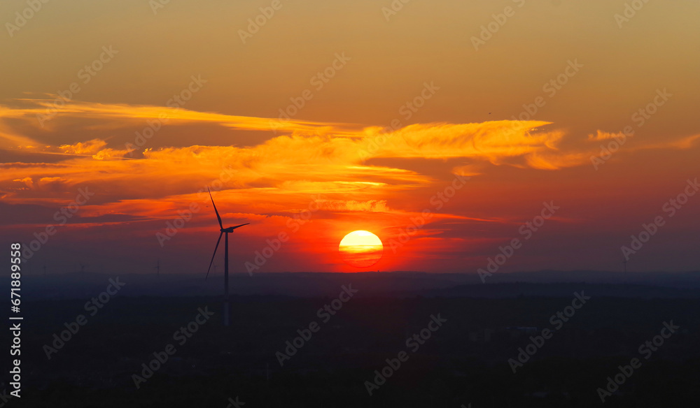 Zachód słońca i w tle turbina wiatrowa elektryczna,