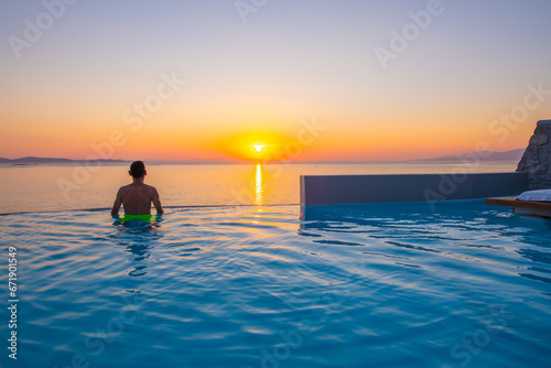 Tourist enjoys at the infinity swimming pool villa at sunset time  Mykonos  Greece