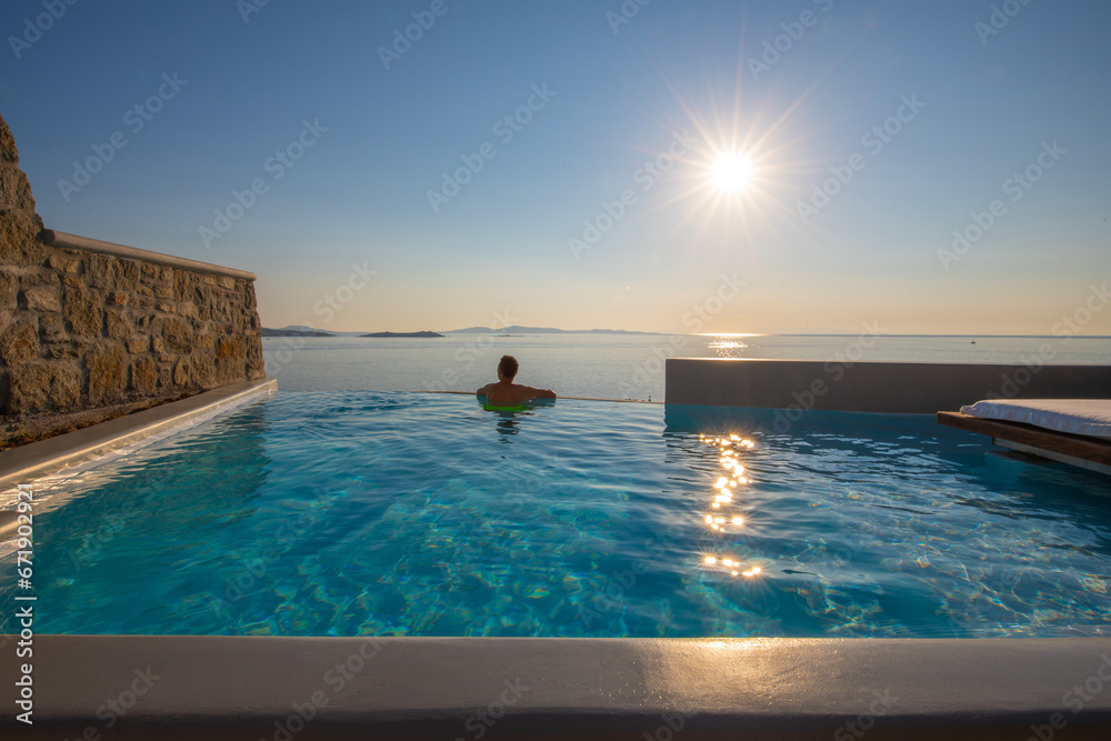 Tourist enjoys at the infinity swimming pool villa at Mykonos, Greece
