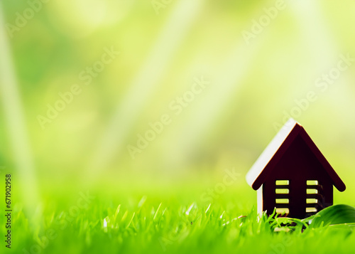 toy house model standing in green grass with a green leave, eco friendly concept, energy efficient solar powered housing