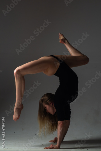 Beautiful woman dancer posing on gray studio background. Flexible sexy woman. Sensual Girl stretching fit slim body. Graceful female gymnast posing with fit perfectly shaped body. Stretching kegs.