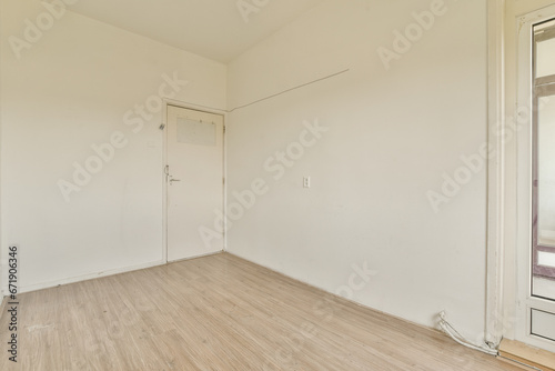 an empty room with white walls and wood flooring on one side, there is a door in the corner