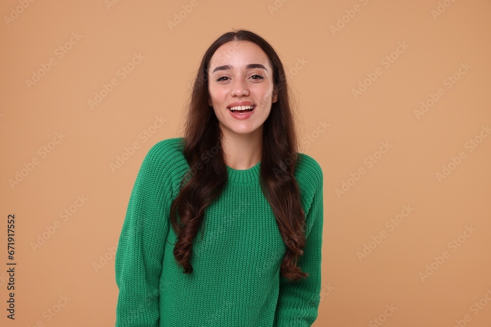 Fototapeta premium Beautiful young woman in stylish warm sweater on beige background