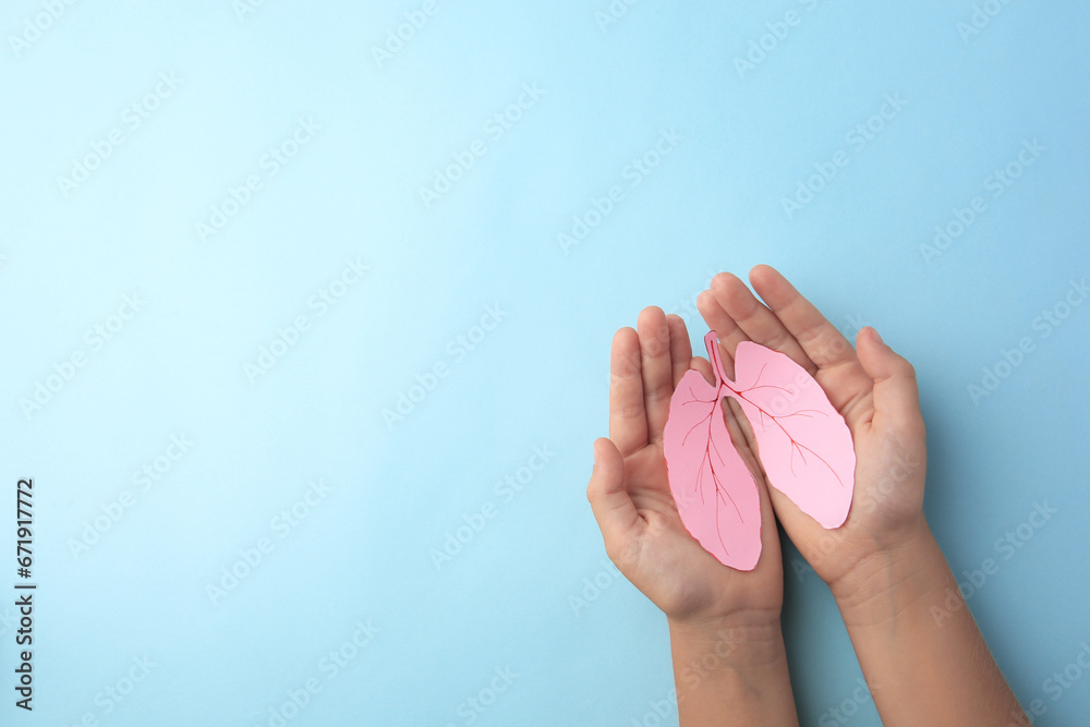 Child holding paper human lungs on light blue background, top view. Space for text - obrazy, fototapety, plakaty 