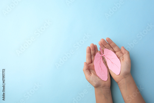 Child holding paper human lungs on light blue background, top view. Space for text photo