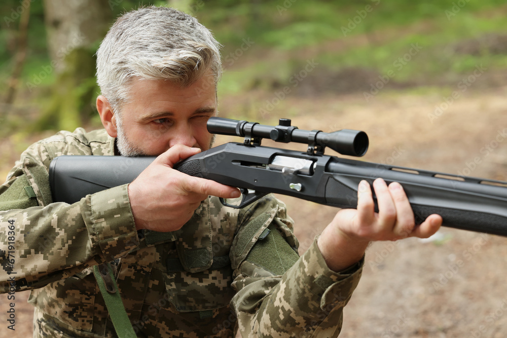 Man aiming with hunting rifle in forest