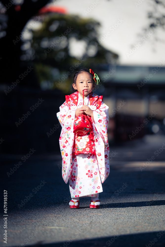 A toddler girl walking on the street wearing a red Japanese kimono. A toddler girl walking on the street wearing a red Japanese kimono.