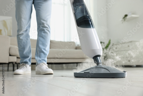 Man cleaning floor with steam mop at home, closeup photo