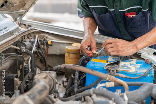 A mechanic tightens the battery terminals with a wrench. photo