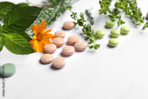 Different pills, herbs and flower on white background, closeup with space for text. Dietary supplements