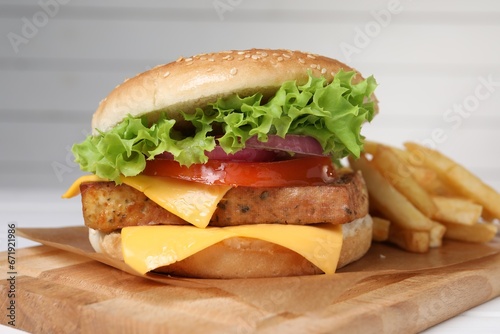 Delicious tofu burger served with french fries on wooden board, closeup