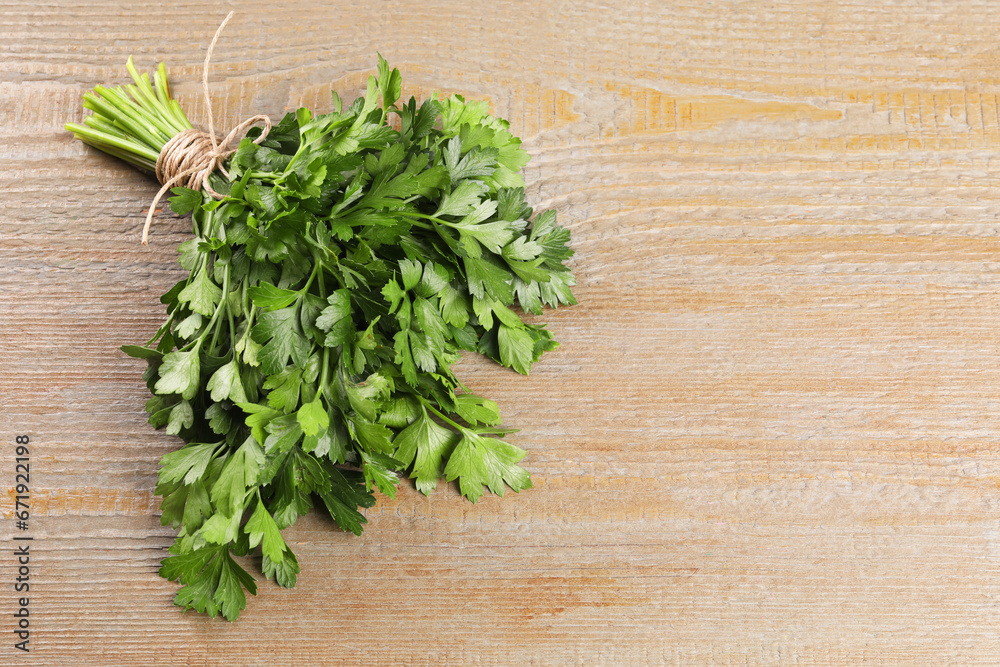 Bunch of fresh green parsley leaves on light wooden table. Space for text Bunch of fresh green parsley leaves on light wooden table. Space for text