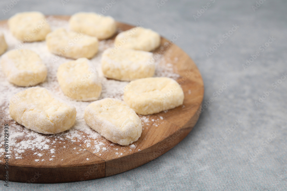 Making lazy dumplings. Board with cut dough and flour on grey table, closeup. Space for text