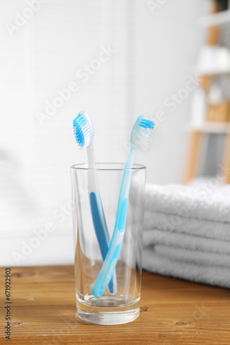 Plastic toothbrushes and towels on wooden table in bathroom © New Africa