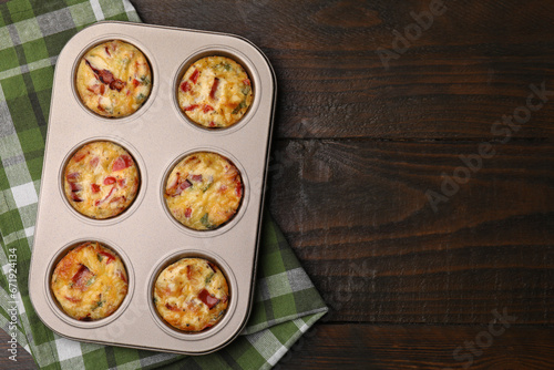 Freshly baked bacon and egg muffins with cheese in tin on wooden table, top view. Space for text