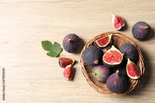 Whole and cut ripe figs with leaf on wooden table, flat lay. Space for text