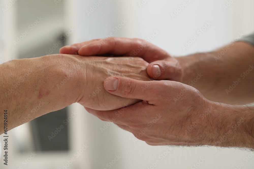 Trust and support. Men joining hands indoors, closeup