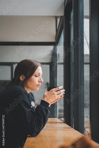 Portrait of young woman drinking coffee at table in cafe Free Download Portrait of young woman drinking coffee at table in cafe - GFXLoad