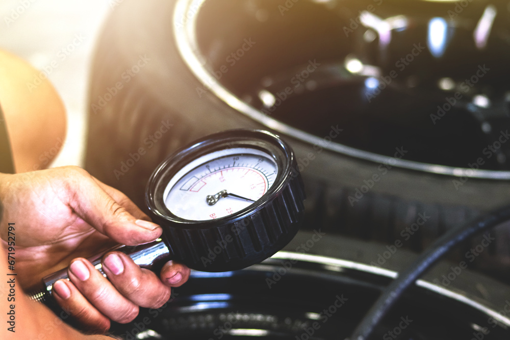Mechanic using a pressure gauge to measure the pressure of the car. - obrazy, fototapety, plakaty 