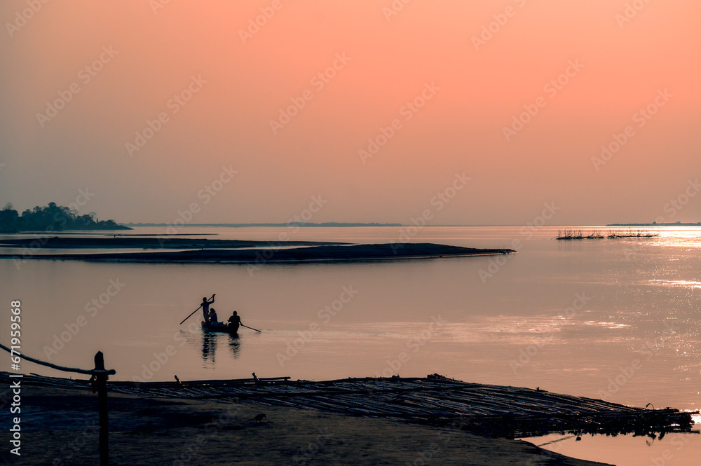 Silhouette of a person on a boat.  Fishermen at the golden hour. Scenic view of Brahmaputra river, Dibrugarh, Assam, India.