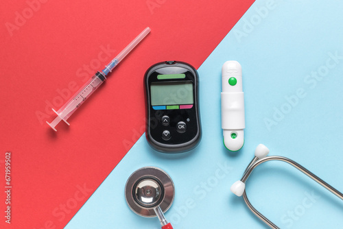 Glucose meter, syringe and stethoscope on a red and blue background. The concept of getting rid of diseases.