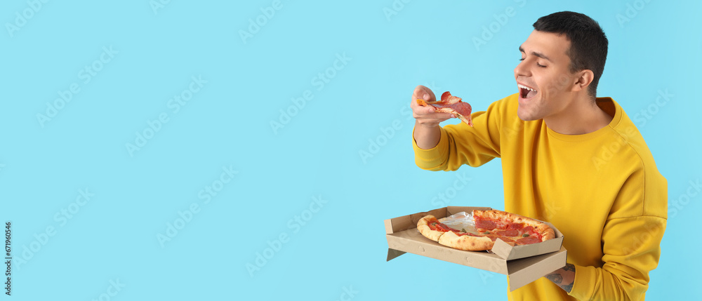 Happy young man eating delicious pizza on light blue background with space for text Happy young man eating delicious pizza on light blue background with space for text