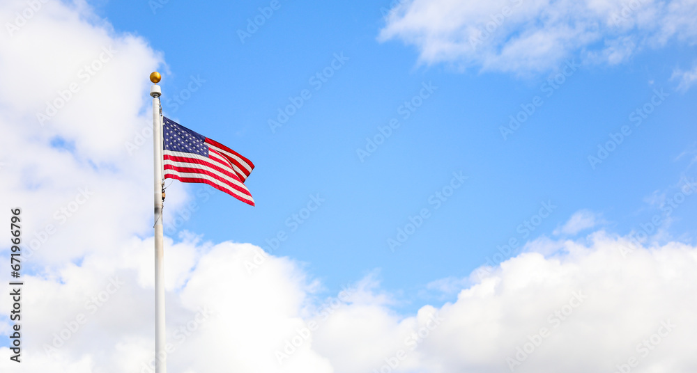 American flag, proudly waving against a clear blue sky, symbolizing freedom, unity, patriotism, and the spirit of the United States