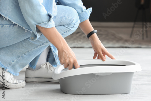 Woman with scoop and litter box for cat in living room